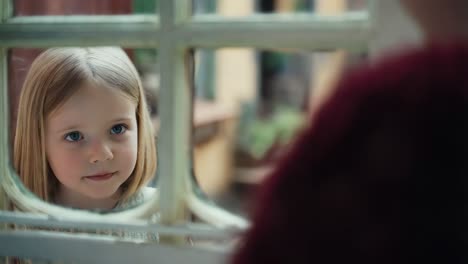 little girl looking through a window