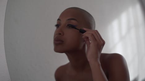 serious black woman applying mascara on eyelashes