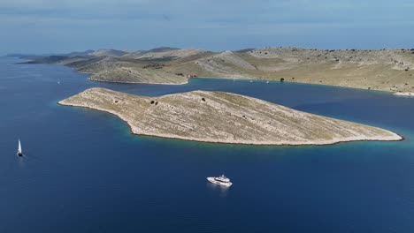 aerial kornati island with rocky sloping shoreline and deep blue waters under clear skies, yachts and sppedboats anchored offshore