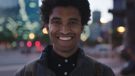 retrato en primer plano de un apuesto joven de raza mixta sonriendo alegremente a la cámara disfrutando de una tranquila noche urbana en la ciudad viajando