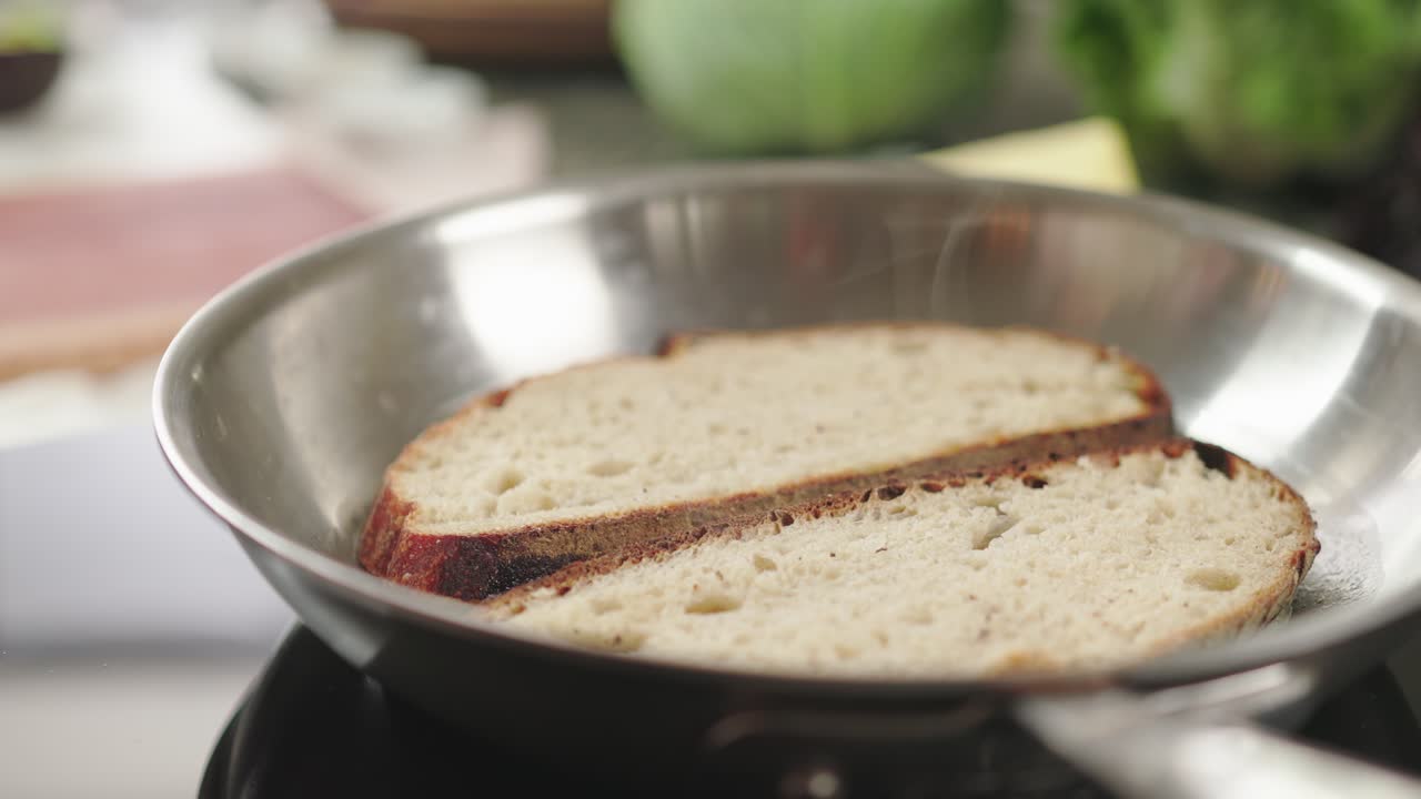 A close-up of two slices of bread toasting in a skillet, suggesting cooking warmth