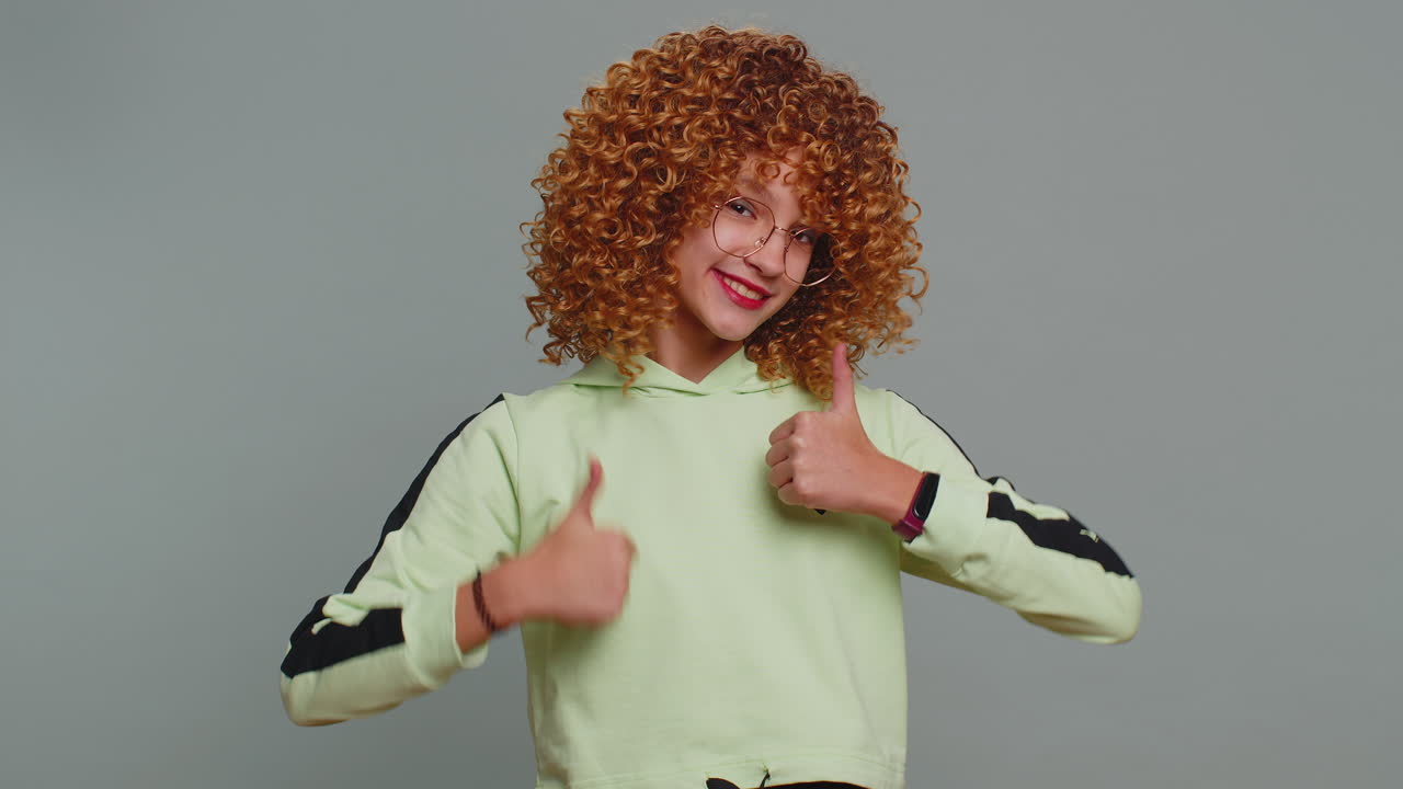 Happy teenager child girl kid looking approvingly at camera showing thumbs up like positive sign
