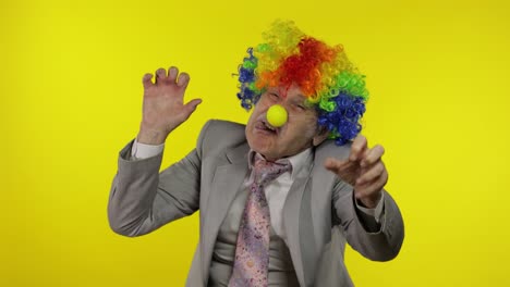 Senior-clown-businessman-entrepreneur-boss-making-silly-faces.-Yellow-background