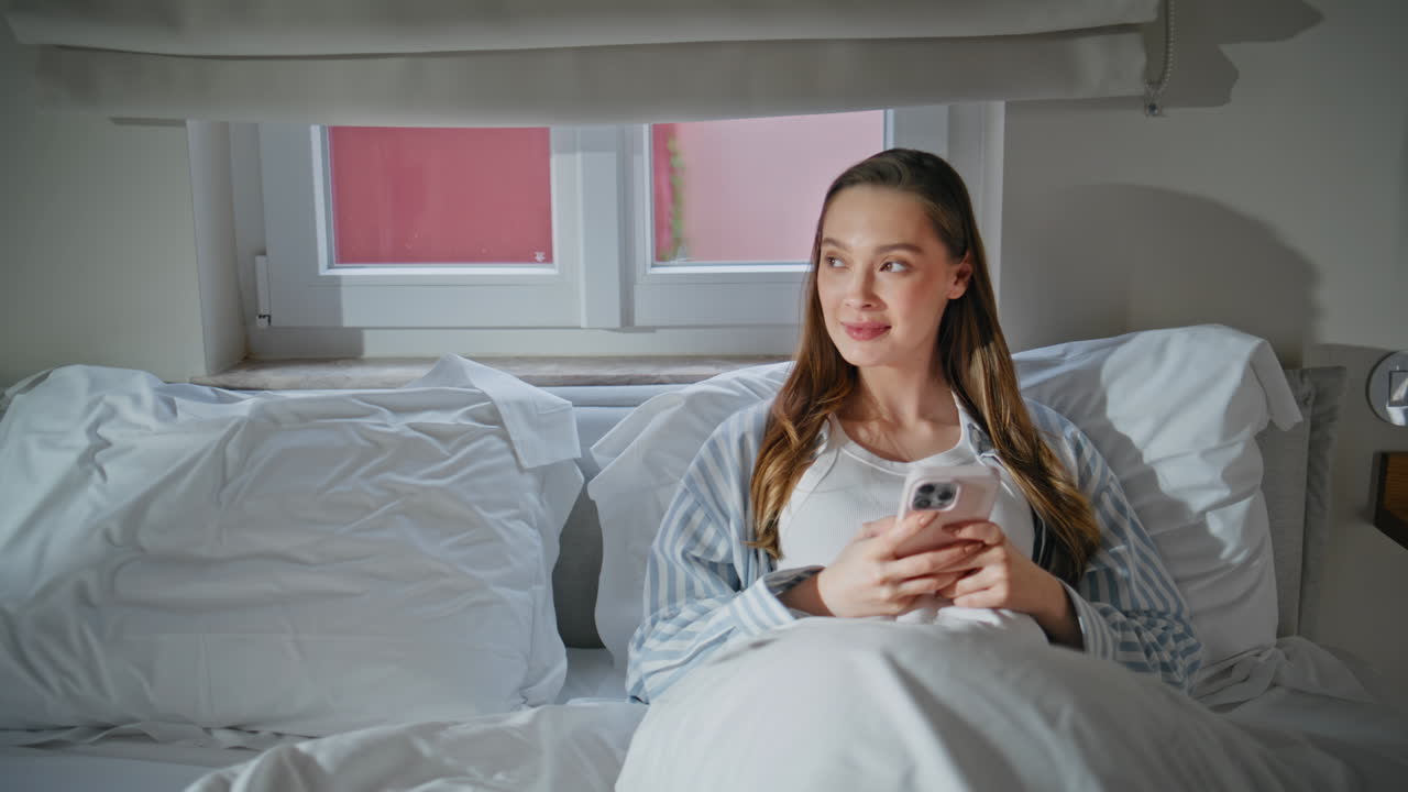Resting girl messaging cell phone lying cozy bedroom closeup. woman