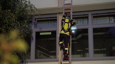 firefighter climbs up a ladder on large building