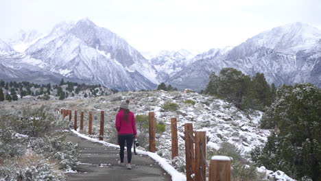 Female-Landscape-Photographer-Walking-on-Mountain-Path-in-Cold-Winter-Scenery-of-Sierra-Nevada-Mountains,-California-USA