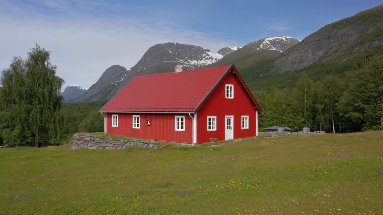 Et levende rødt hus plassert mot et fantastisk fjellandskap med et grønt jorde