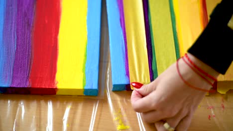 a woman using painters tape to finish her colorful stripes on a canvas