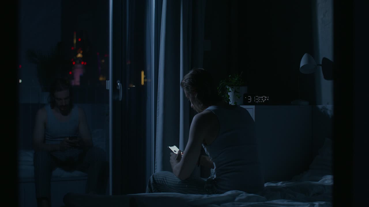 夜ベッドでスマートフォンを使っている男性