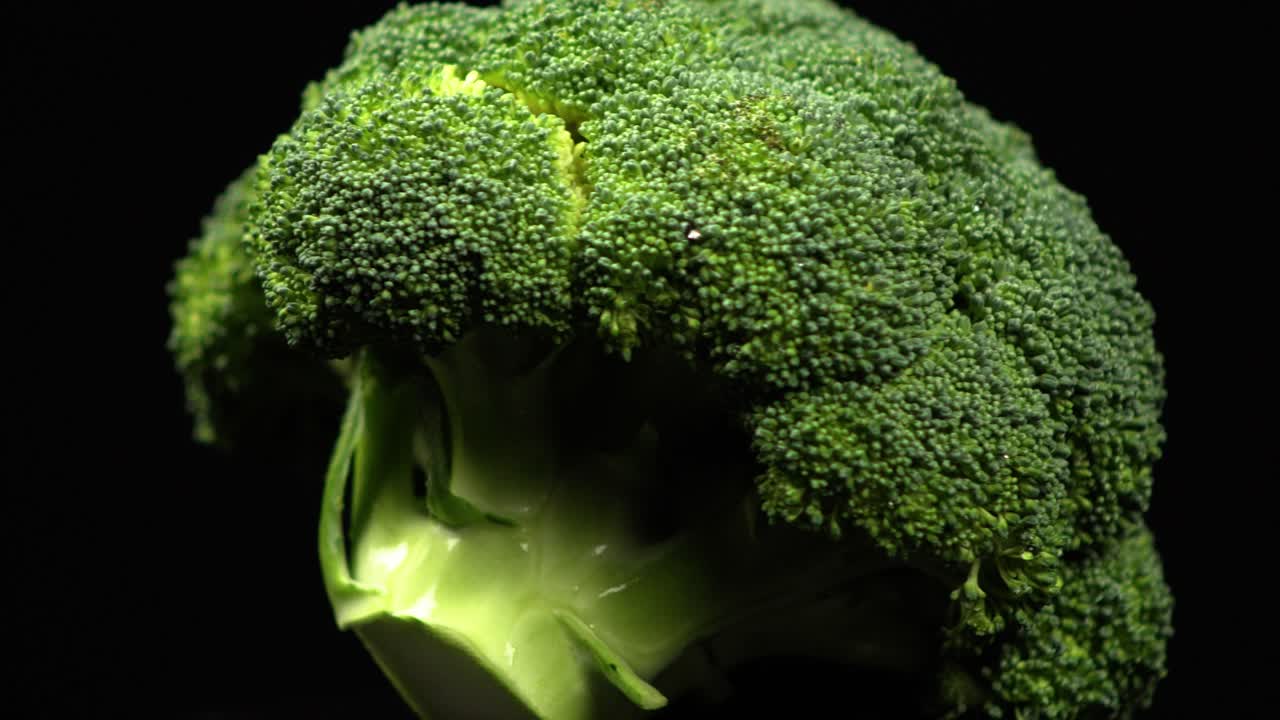 Close up macro of fresh big broccoli rotating on a black background