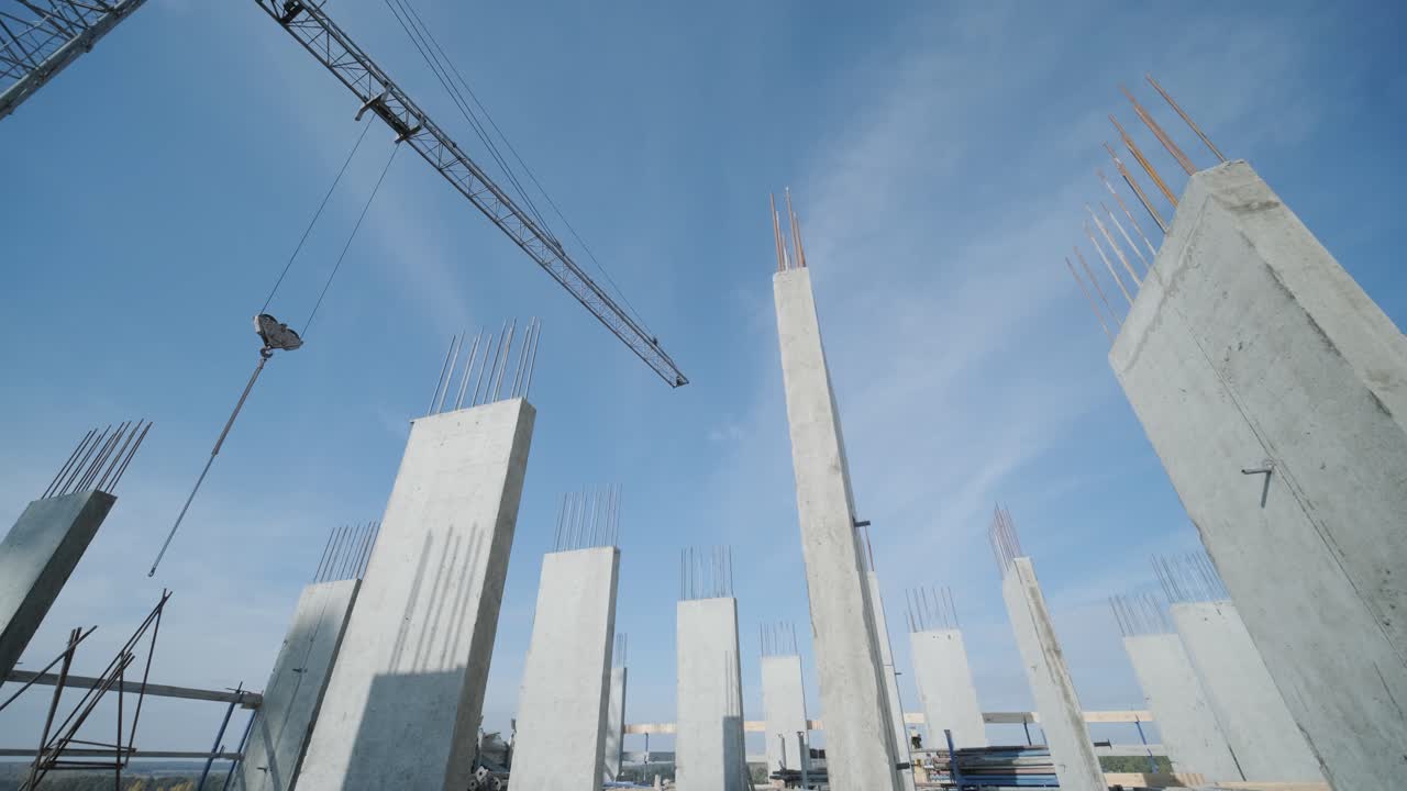 las grúas de torre trabajan en la construcción de edificios residenciales de ladrillo contra el fondo de un cielo azul.