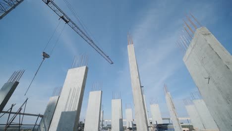 tower cranes work on the construction of brick residential buildings against the background of a blue sky.