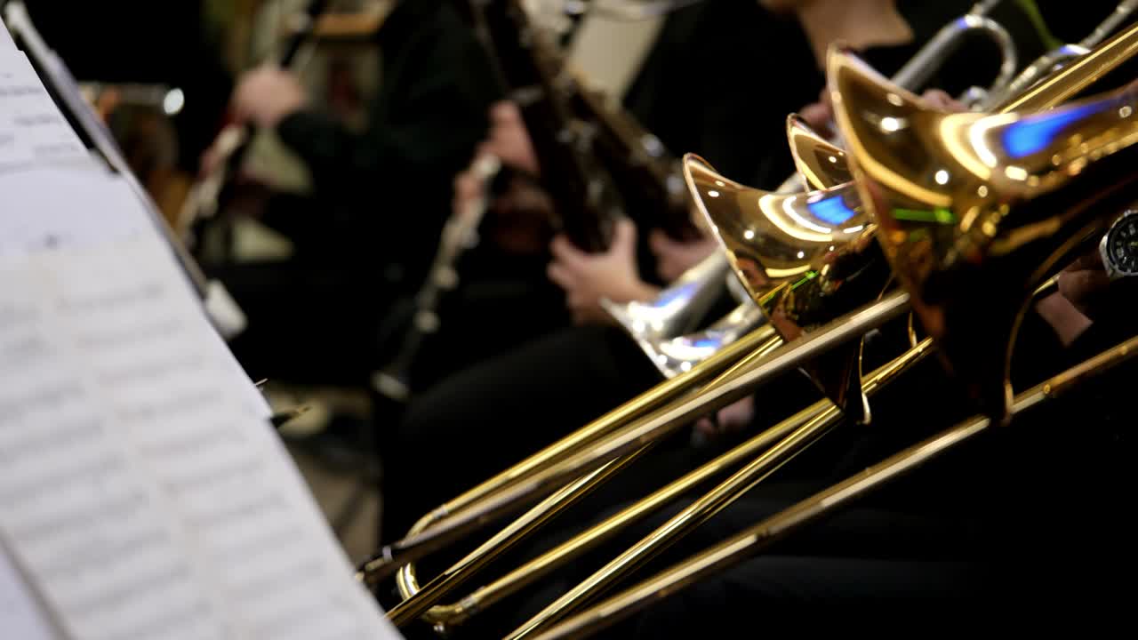 disparo lateral de varios músicos tocando sus trombones y otros músicos tocando sus instrumentos