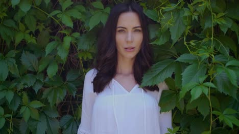 stylish hipster girl posing over green leaves bush background