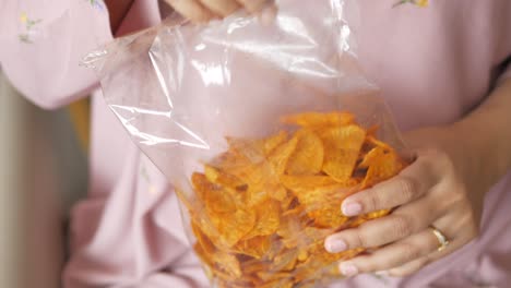 mujer comiendo papas fritas de tortilla picante de una bolsa de plástico