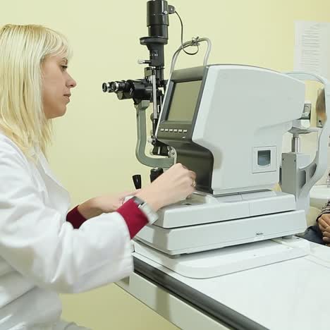 female pediatric optician examining eyes of little boy with slit lamp device. eye examination