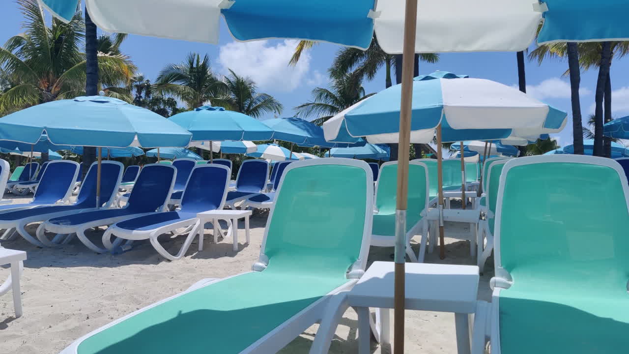 Rilassati in stile caraibico: sedie a sdraio e ombrelloni vuoti adornano le spiagge sabbiose sullo sfondo di acque e cieli azzurri, incarnando la tranquillità tropicale