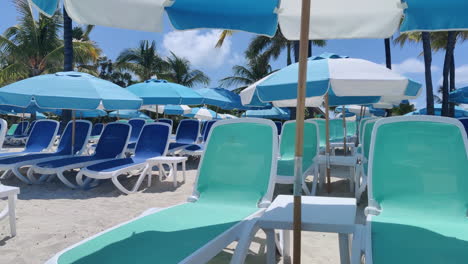 Relájese-Al-Estilo-Caribeño:-Sillas-De-Playa-Vacías-Y-Sombrillas-Adornan-Las-Costas-Arenosas-Con-El-Telón-De-Fondo-De-Aguas-Y-Cielos-Azules,-Personificando-La-Tranquilidad-Tropical