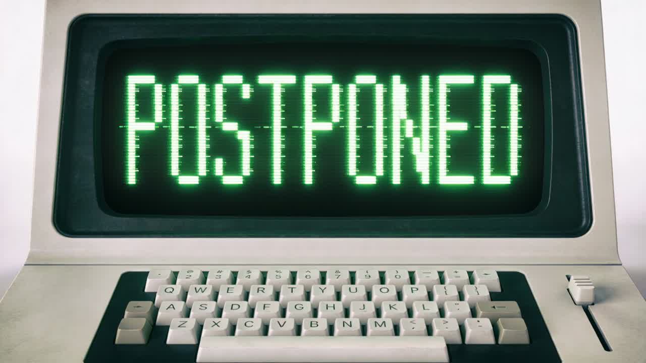 Displaying CRT screen showing POSTPONED and flickering from glitch at desk with beige keys, slider