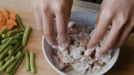 hands mixing food with flour in a bowl for cooking preparation
