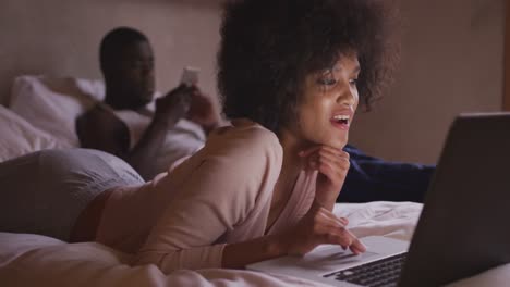 couple on smartphone or computer in bedroom