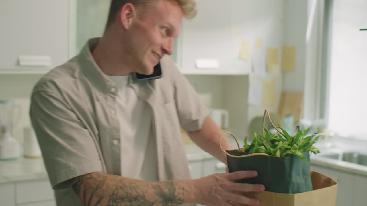 Man Unloading Groceries and Talking on Phone at Home
