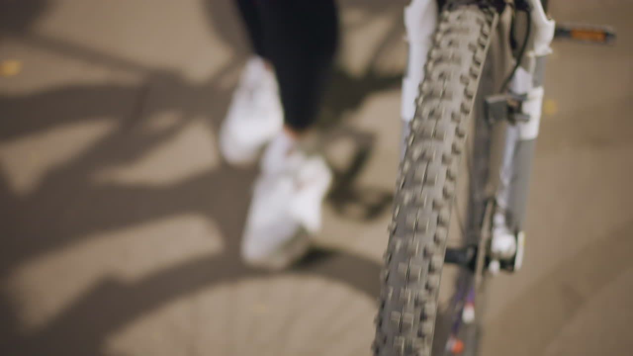 Calzature e bici che si muovono in un parco notturno, parco cittadino a tarda sera con scarpe e bicicletta in movimento, scena di un parco urbano notturno che mostra scarpe che camminano accanto al pneumatico di una bicicletta con illuminazione soffusa