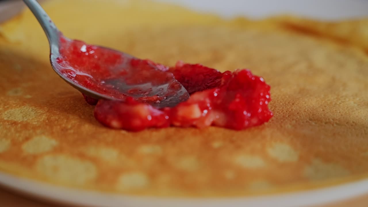 Creamy strawberry blend gently spreads across crepe in slow and soothing motion