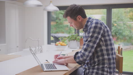 man working from home using laptop on kitchen counter - shot in slow motion