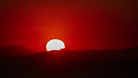 full moon rising against red horizon over mountains