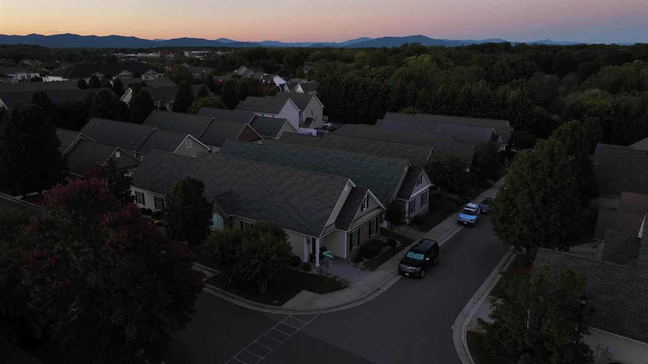 Parking Car on street of modern american neighborhood with one family houses in row. Golden sunset in USA at dusk. Aerial wide shot. Classical homes with grey roof in quiet suburbia