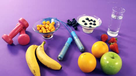 pesas, plátano, vaso de agua, fruta, cuerda para saltar y desayuno