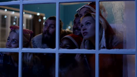 excited friends looking out in window during christmas