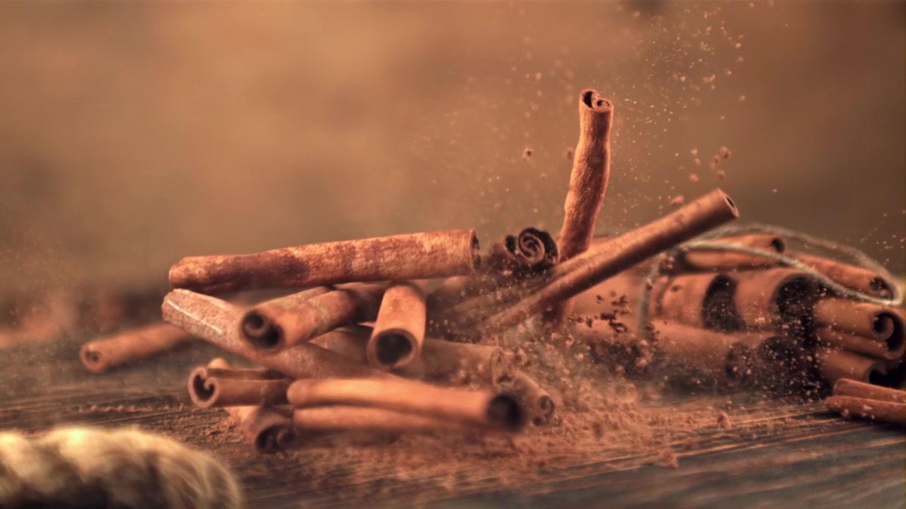 Kanelstenger som faller ned på malt kanel i sakte film