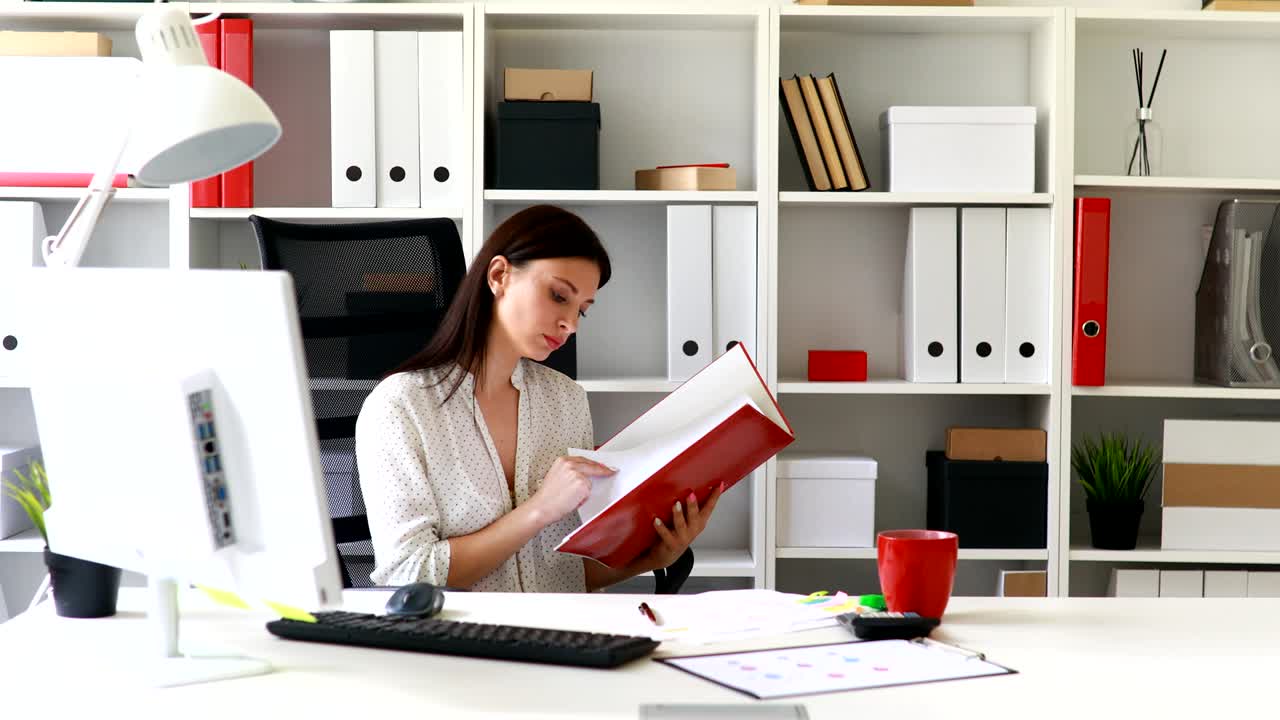 mujer de negocios en blusa blanca examinando documentos en la carpeta