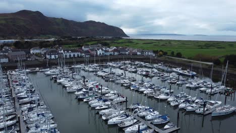 Szenisch-Luxuriöses-Hafenapartmentdorf-Am-Wasser,-Yachten-Und-Segelboote-Unter-Der-Bergküste,-Langsame-Überführung-Aus-Der-Luft