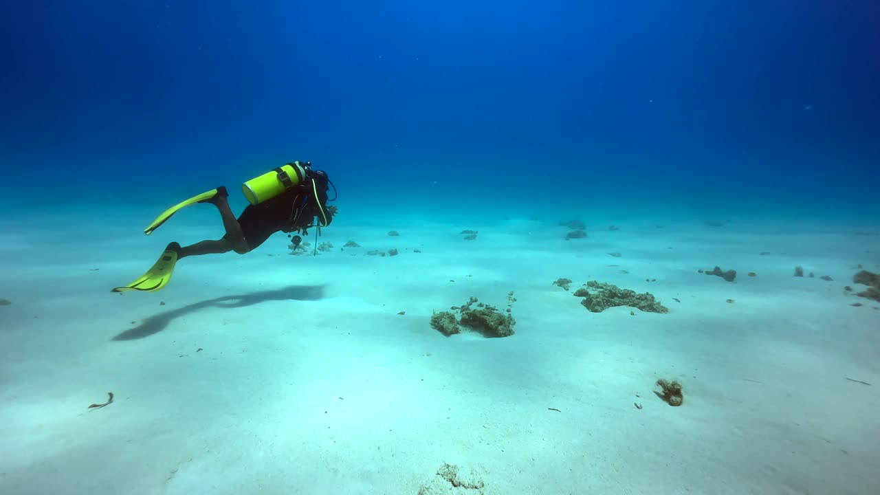 Diver swimming above the sandy bottom near Mnemba Island. Zanzibar, Tanzania.