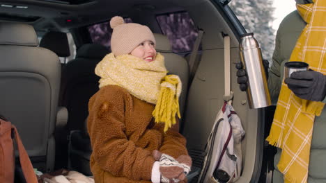 Teenage-Girl-Dressed-In-Winter-Clothes-Sitting-In-The-Trunk-Of-A-Car