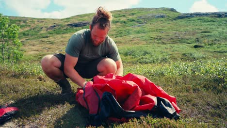 portrait of a caucasian hiker keeping his tent after camp on a sunny day