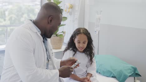 Happy-diverse-doctor-examining-girl-with-otoscopy-in-hospital-in-slow-motion