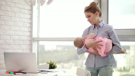 Mom-holding-baby-on-hands-in-office.-Sleeping-infant-in-mother-embrace