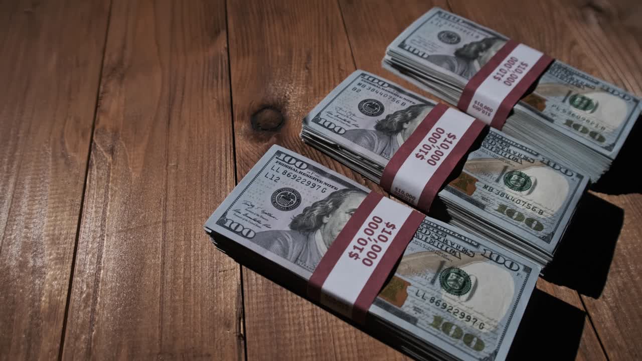 Three Stacks of 10000 American Dollars Banknotes in Bundles Lie on Wooden Table