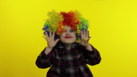 una niña payasa con una peluca colorida haciendo caras tontas. divirtiéndose, cantando, bailando. halloween