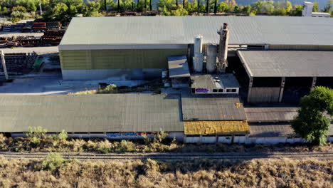 industrial building with three chimneys on a sunny day next to a lake, aerial
