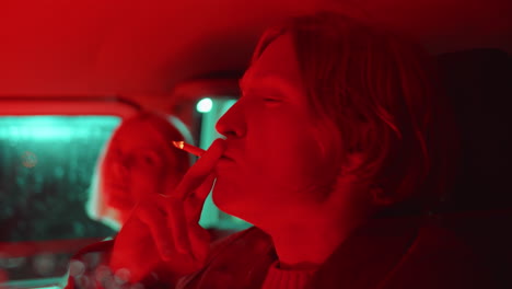 young couple smoking in car with red light