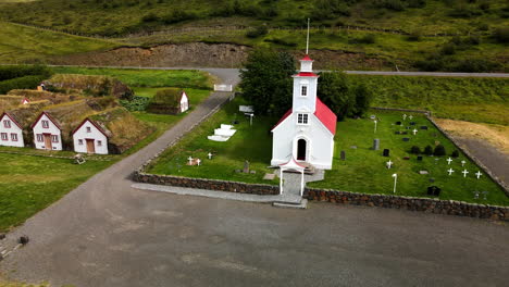 aerial circular shot of a white church with red roof and a graveyard