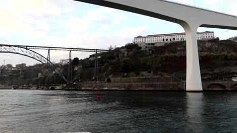 Douro-River-exploration-with-red-buoy-under-white-Ponte-de-Sao-Joao,-and-Maria-Pia-bridge-backdrop