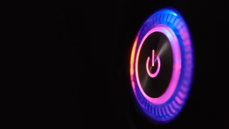 un bucle de video macro de 4k de un botón de encendido de la computadora en la unidad del sistema sobre un fondo negro.