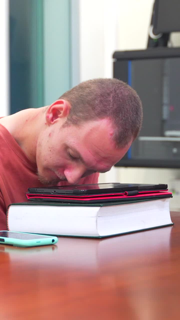 Uomo addormentato sui libri con cellulare e tablet