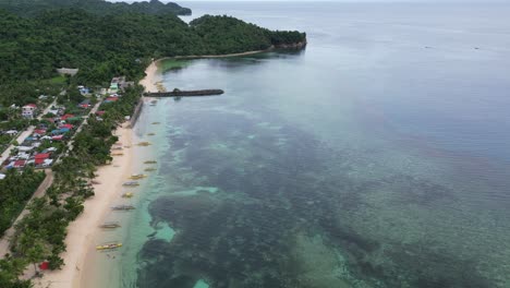 Aerial-view-of-a-stunning-tropical-island-village-with-small-yellow-boats-and-a-coral-reef,-showcasing-the-beauty-of-Asian-beach-life,-stunning-tourism-scene